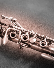 Obraz premium Close view of a silver flute resting on a textured surface in a dimly lit room during the evening hours