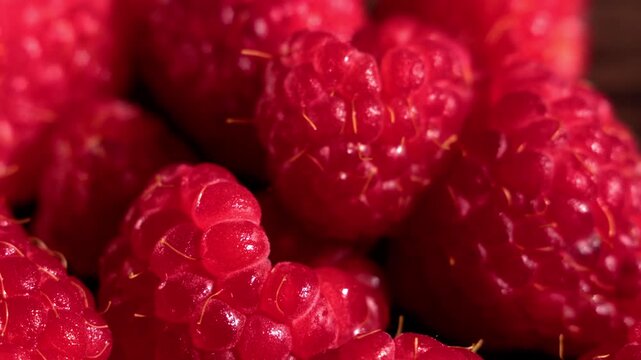 Slow backward motion reveals ripe red raspberry macro texture with rich surface details filling the frame. The macro background works for food advertising, motion visuals, natural design backgrounds.