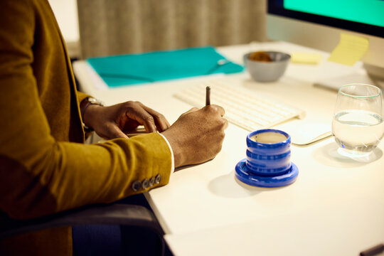 Anonymous man writes at his desk
