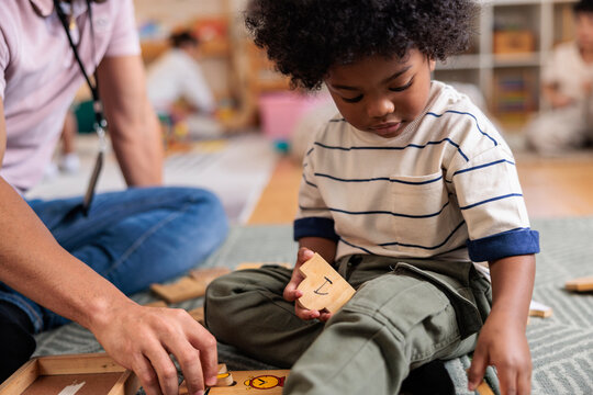 Child learns with wooden puzzle, guided by adult.