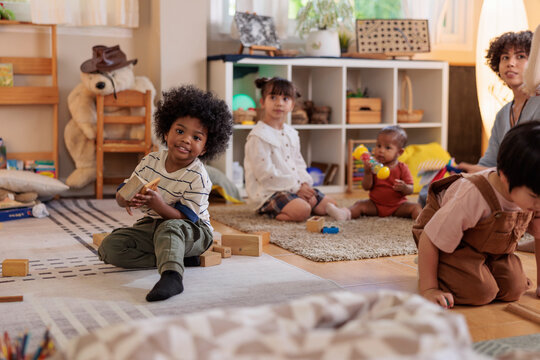 Diverse children play with blocks in a bright classroom.