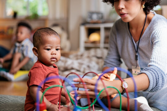 Baby watches adult play with colorful bead maze toy.