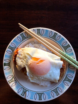 Fried egg over rice with chopsticks on patterned plate