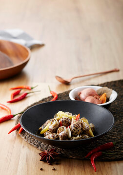Delicate snacks, pickled pepper and garlic snails, on a wooden table