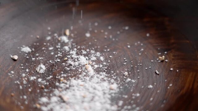 Fine sugar mixed with grated lemon zest falling into an empty wooden bowl in slow motion. Baking ingredient