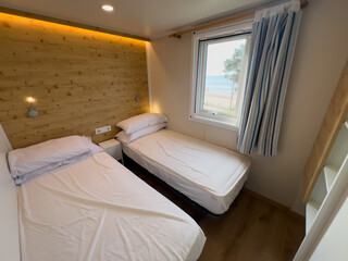 Fototapeta premium Modern bedroom with two beds and a view of the sand and sea through the window