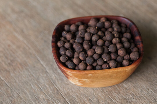 Black peppercorn in a wooden bowl on tabletop