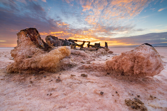 Rusty machinery encrusted with salt crystal under a colorful sunrise