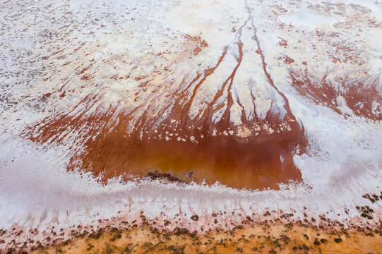 Rusty colored minerals seeping into a dry salt lake bed