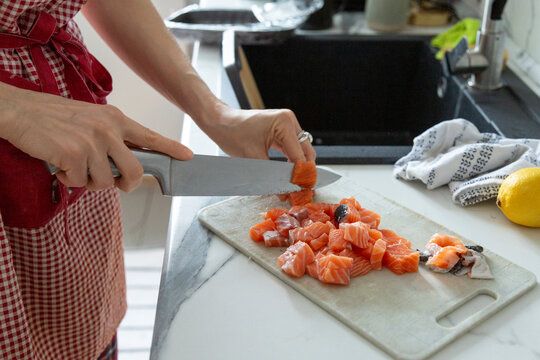 Person chopping fresh salmon fillets on a cutting board