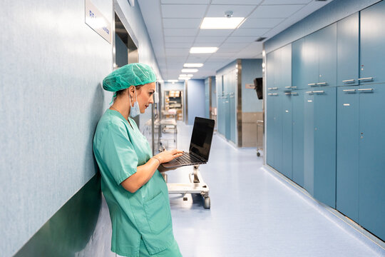 Female surgeon checking laptop in hospital corridor
