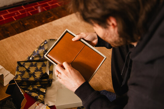 Man opening a gift box with a brown leather notebook 