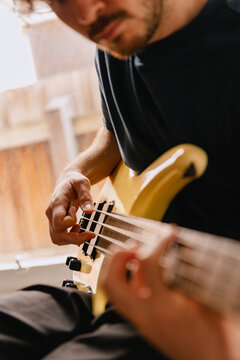 The hands of a man who is playing a bass guitar 