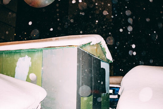 Heavy snowfall covers parked vehicles and a street