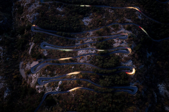 Winding Road Through Mountains at Night With Car Headlights Visible