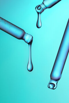 Three glass pipettes with liquid on gradient blue and green backdrop.
