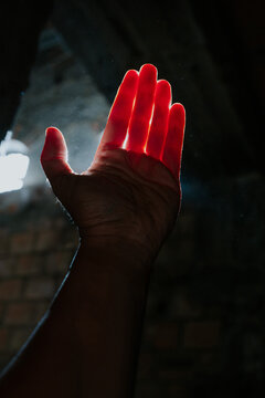 Hand illuminated by light with dark background