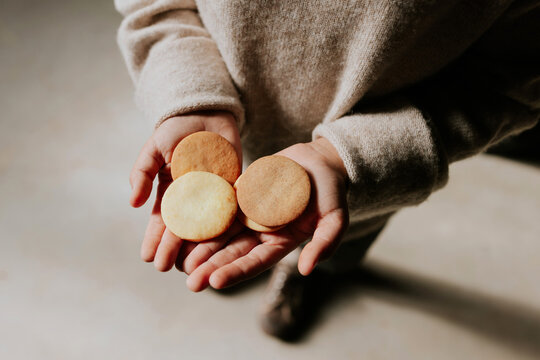 Kid hands gently holding three round cookies