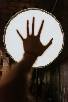 Silhouette of a hand against bright light in dark room
