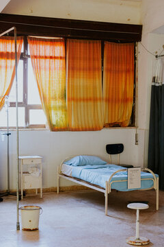 Empty abandoned hospital room with old bed and rusty equipment