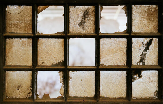 Weathered window with broken panes in rustic setting