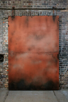 Industrial rusty metal door against a brick wall