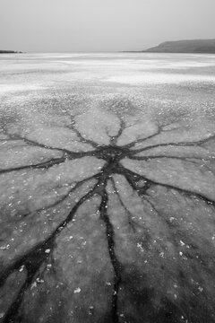 Frozen lake with ice cracks forming pattern