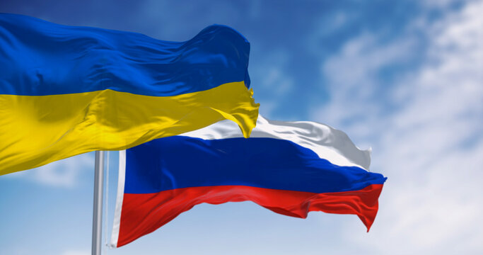 National flags of Ukraine and Russia waving on a clear day