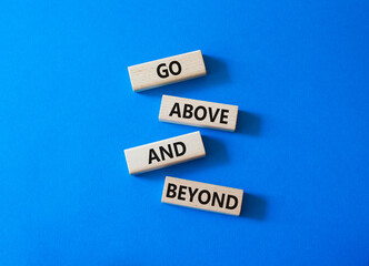 Fototapeta premium Go above and beyond symbol. Concept words Go above and beyond on wooden blocks. Beautiful bright blue background. Business and Go above and beyond concept. Copy space.