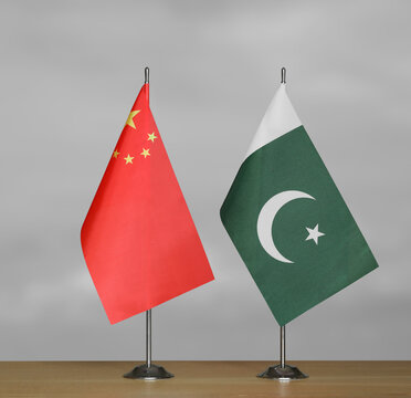 Two table flags of the China and Pakistan on a blurred gray background