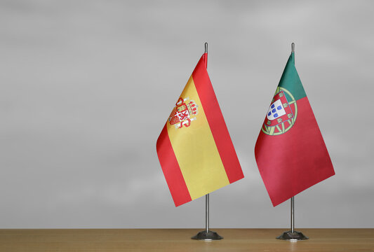 Two table flags of the Spain and Portugal on a blurred gray background