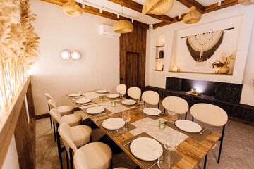 Obraz premium Cozy boho private dining room with long table setting and warm lighting