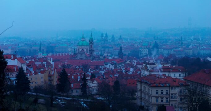 Wide winter overview of Prague Old Town from Strahov Monastery. Blue early morning atmosphere highlights historic architecture and iconic landmarks in a calm, cinematic cityscape.