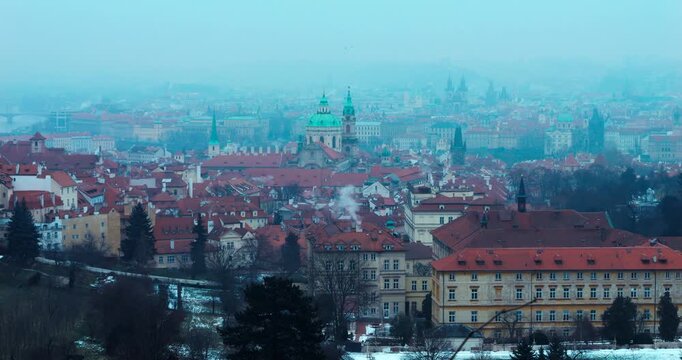 Wide winter overview of Prague Old Town from Strahov Monastery. Blue early morning atmosphere highlights historic architecture and iconic landmarks in a calm, cinematic cityscape.
