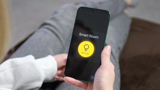 Effortless home automation. User turns on smart room lights using a mobile app. High-quality close-up showing intuitive IoT interface and glowing bulb icon. Perfect for smart home technology, energy