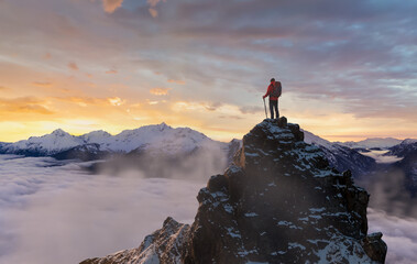 Hiker On Snowy Peak At Sunrise Above Clouds In Majestic Mountain Range