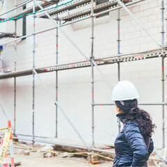 Fototapeta premium a construction site scene, focusing on a woman in a hard hat who appears to be observing the ongoing work.