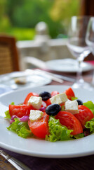 Fresh Mediterranean salad served on a plate with seaside restaurant background.
