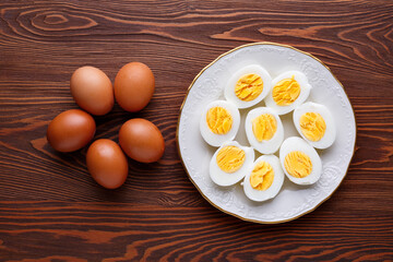 Hard-boiled chicken eggs lie on a white plate on a dark wooden table