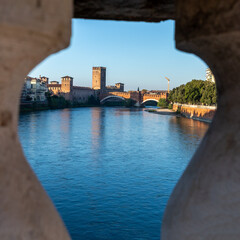 Historic bridge over Adige River framed by stone arch in Verona, Italy
