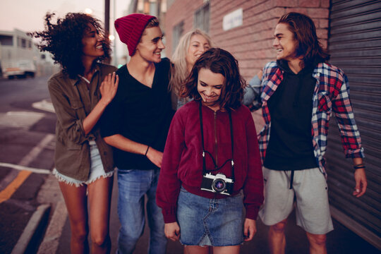 Young friends walking and laughing on urban street at dusk