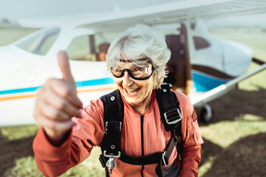 Senior woman skydiver giving thumbs up at airfield