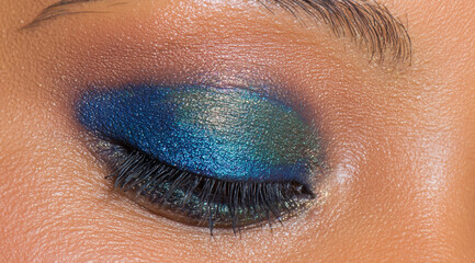Woman eye with vibrant blue and green eyeshadow makeup. Creative beauty look for cosmetic and fashion industry.