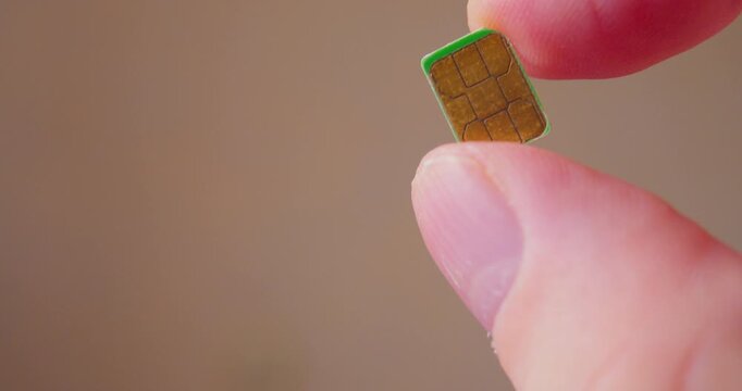 Modern technologies. Close-up video of fingers holding a SIM card designed for smartphone.