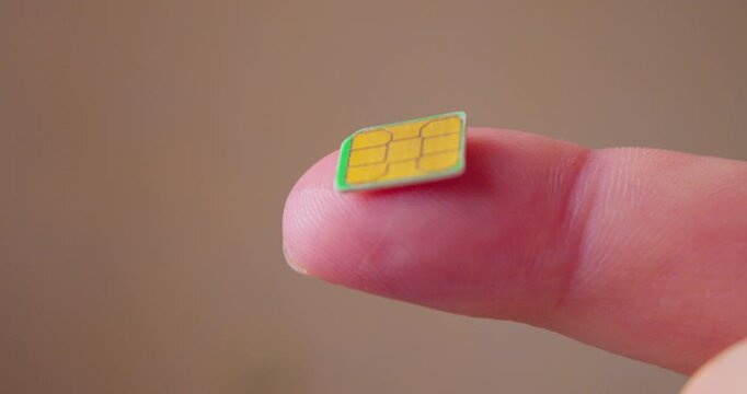 Macro view of a tiny SIM card designed for smartphone lying on a finger.