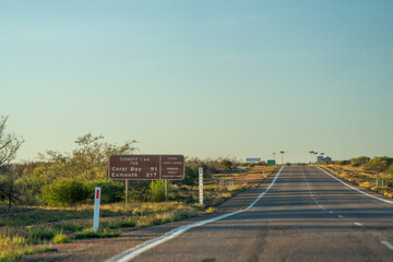 Obraz premium Australian road signs directing to Coral Bay along North West Coastal Highway in Western Australia outback landscape with blue sky