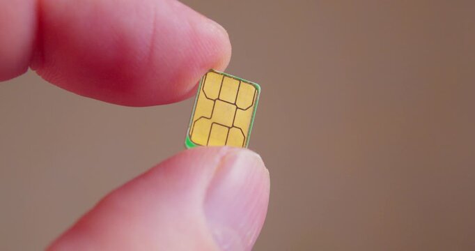 Detailed close-up of fingers grasping a SIM card compatible with smartphone.