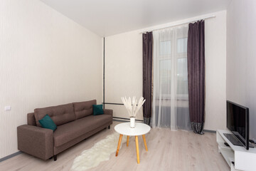 Bright minimalist living room with sofa, TV stand, round coffee table