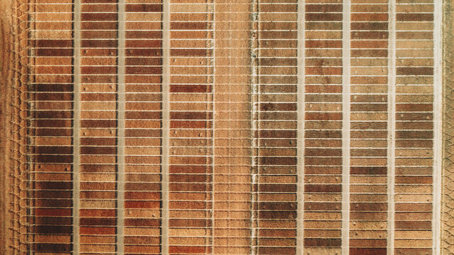 Aerial view of rows of rectangular structures, a tapestry of earthy browns and tans, in stark geometric contrast to the surrounding landscape, Greoux-les-Bains, Provence-Alpes-Cote d'Azur, France.