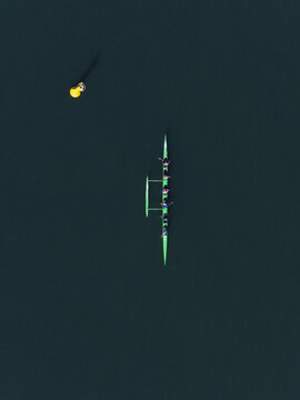 Aerial view of a slender rowing boat slicing through the dark, glassy waters near 4 Caporn Street, creating a striking contrast, Mosman Park, Western Australia, Australia.